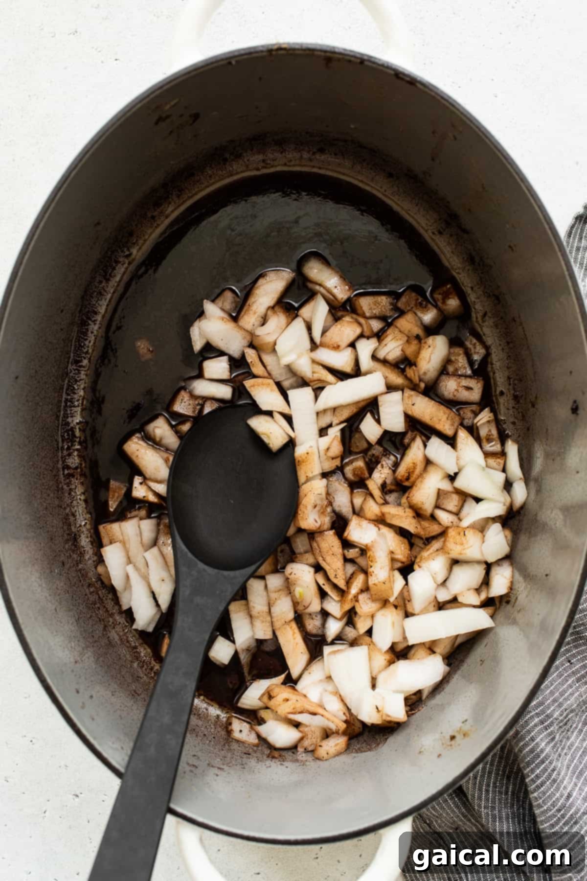 Building Flavor: Sautéing Onions After Deglazing Diced white onions beginning to sauté in a Dutch oven, surrounded by the remnants of deglazing liquid. They soften and absorb rich flavors, preparing for the next layer of ingredients.