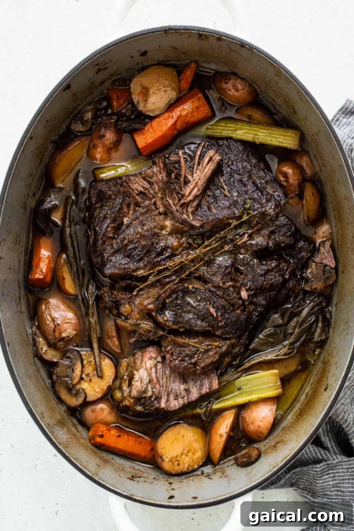 Dutch Oven Pot Roast: A Hearty Family Meal A perfectly cooked pot roast resting in a Dutch oven, surrounded by tender carrots, potatoes, and mushrooms, all bathed in a rich, savory gravy, ready to be served family-style.