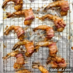Bacon wrapped shrimp secured with toothpicks on a baking sheet.