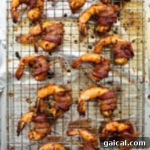 Crispy bacon-wrapped shrimp cooling on a wire rack after being baked.