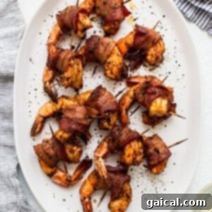 Platter of bacon-wrapped shrimp skewers with fresh pepper.