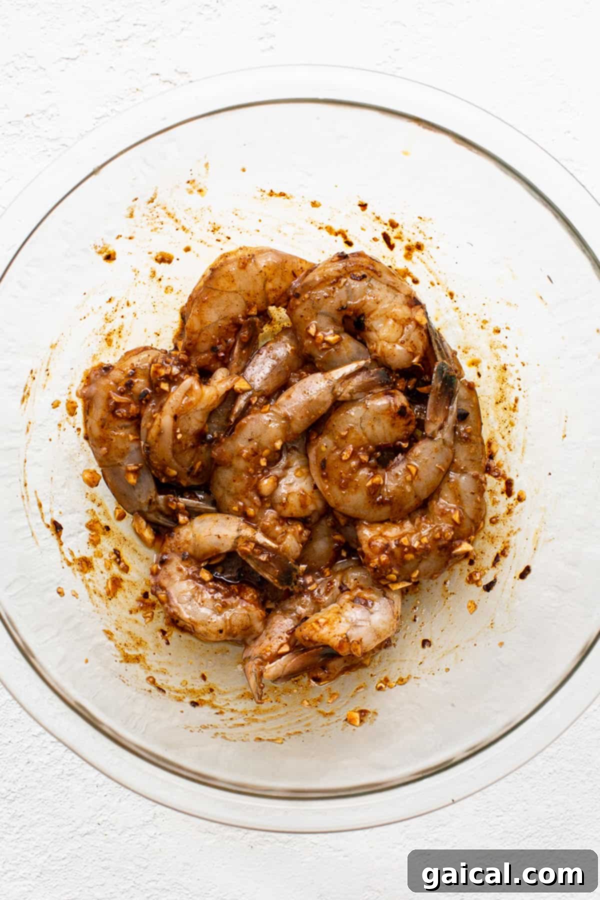 Marinating Shrimp for Optimal Flavor Infusion Raw shrimp soaking in a vibrant, homemade marinade in a clear glass bowl.