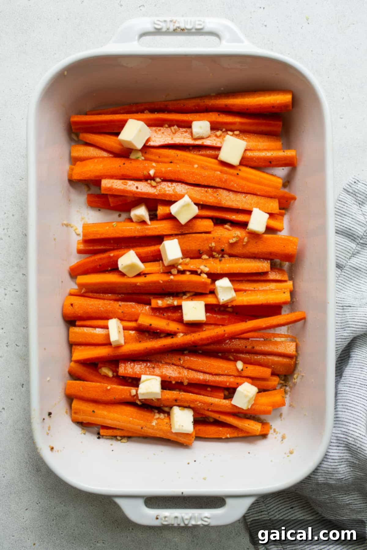 Prepping the Perfect Garlic Butter Carrots for Roasting Carrots prepped in a casserole dish, topped with generous chunks of cold butter, ready for roasting.