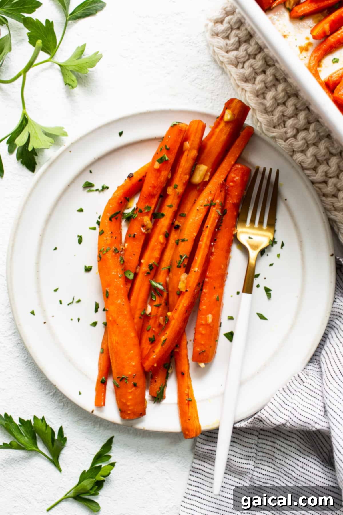 Ready to Enjoy: A Forkful of Garlic Glazed Carrots A plate of roasted garlic glazed carrots with a fork, highlighting their appealing texture and readiness to eat.