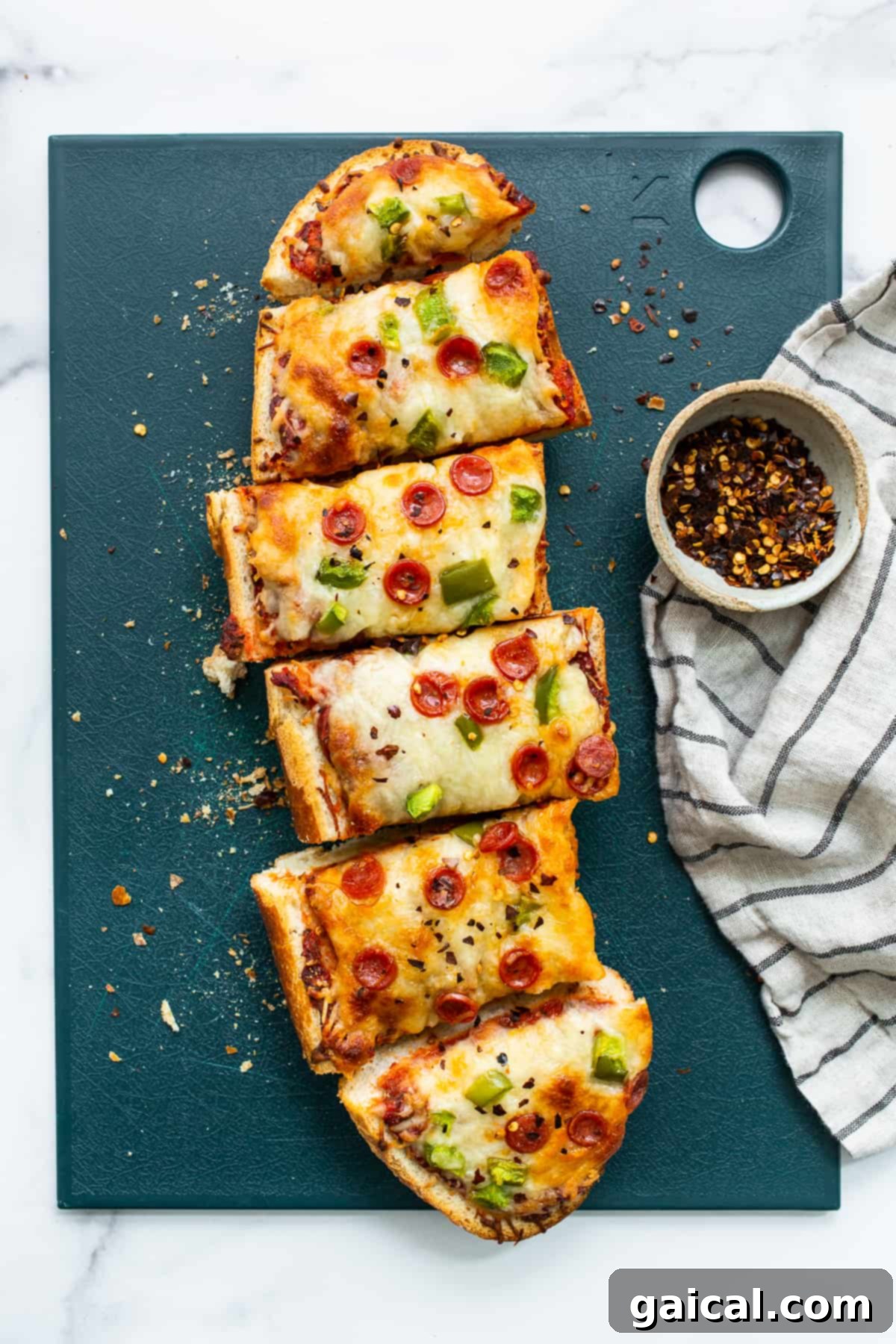 Delicious Homemade French Bread Pizza Ready to Slice Freshly baked French bread pizza topped with pepperoni and green peppers, resting on a wooden cutting board.
