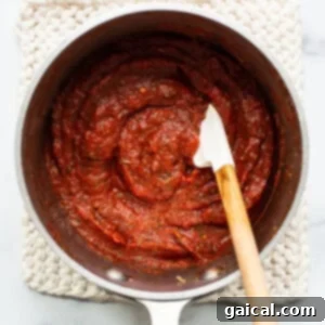 Tomato sauce in a pan with a wooden spoon.
