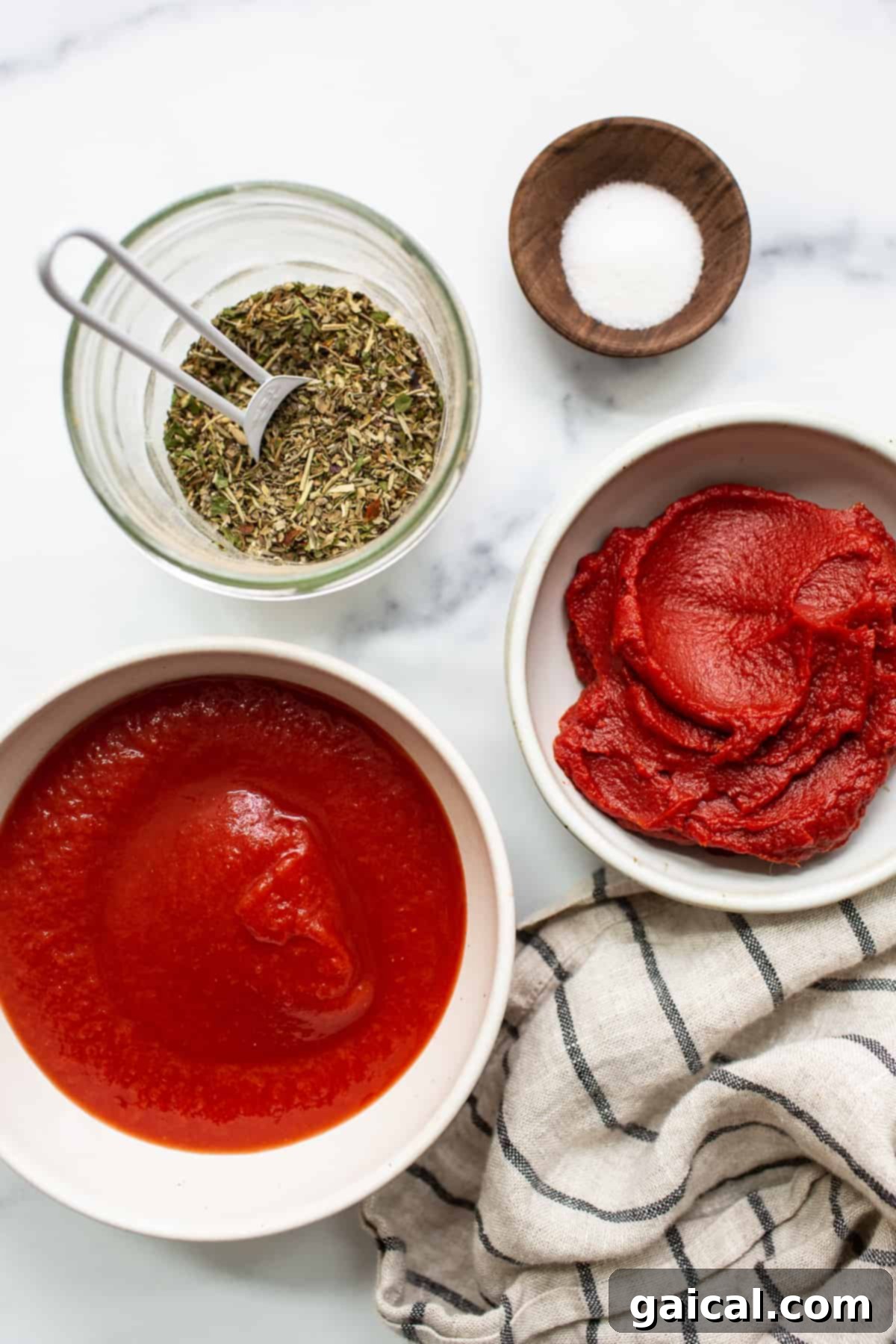 Simple Ingredients for Quick Pizza Sauce Four jars of ingredients laid out for making homemade pizza sauce.