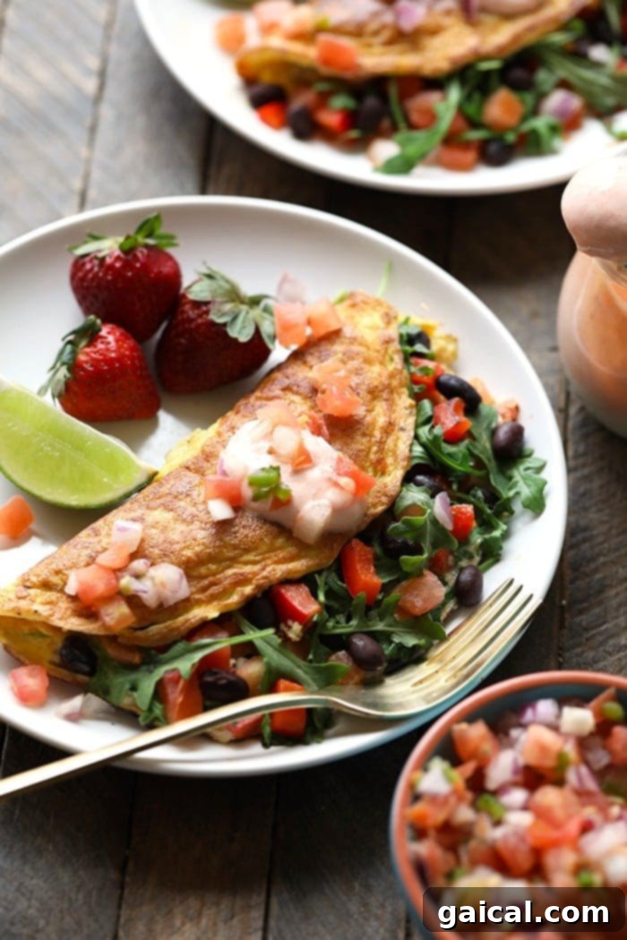 15+ Creative Egg Breakfasts to Kickstart Your Day 19 A colorful plate featuring a veggie-packed omelette with black beans and a side of fresh strawberries.