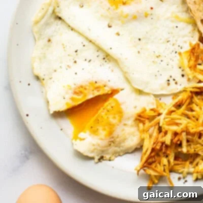 A hearty breakfast plate featuring perfectly cooked over medium eggs, alongside crispy potatoes and golden toast.