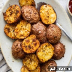 Crispy air fryer potatoes on a plate with ketchup, showcasing their perfectly golden exterior.