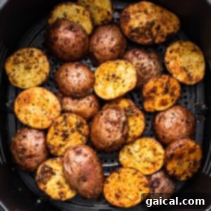 Roasted potatoes in an air fryer basket, half-cooked.