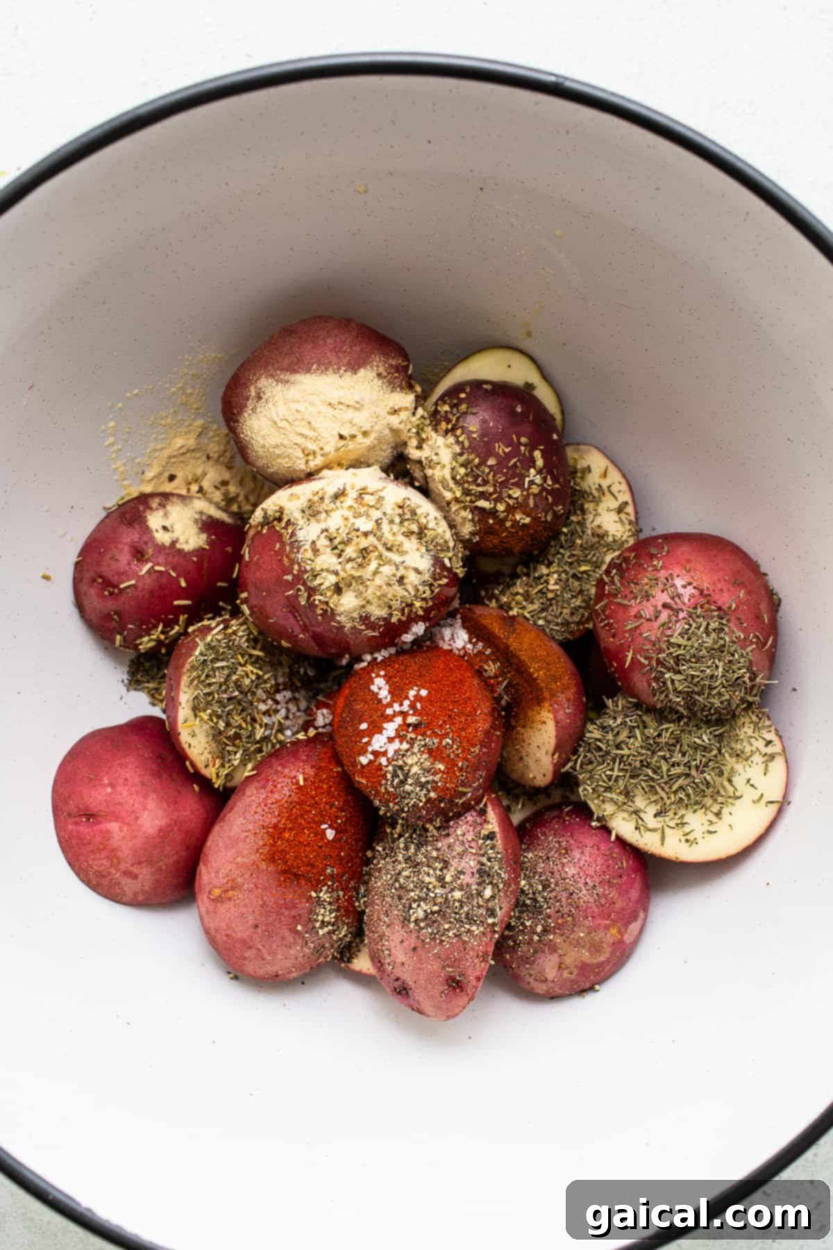 Cut baby red potatoes in a bowl, tossed with olive oil and a rich blend of spices.
