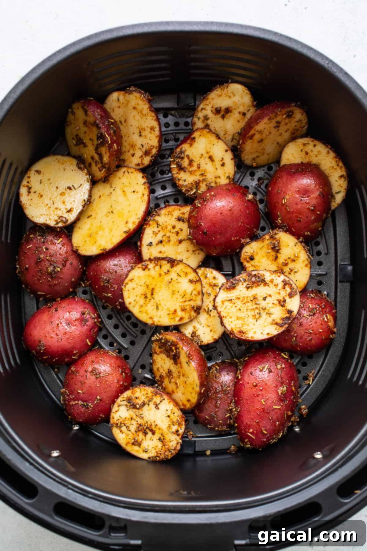 Halved potatoes arranged neatly in an air fryer basket, ready for cooking.