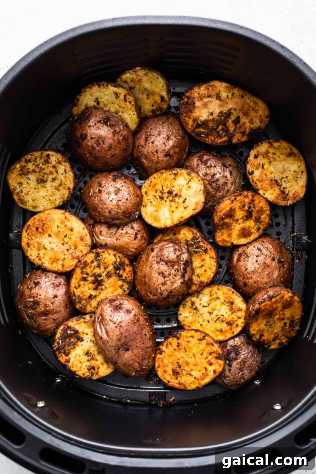 Crispy golden potatoes cooking inside an air fryer basket, showcasing their even browning.