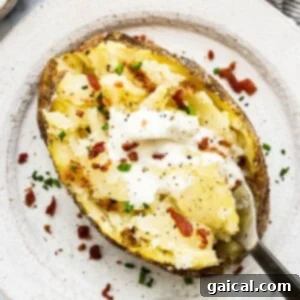 A baked potato topped with sour cream and bacon.
