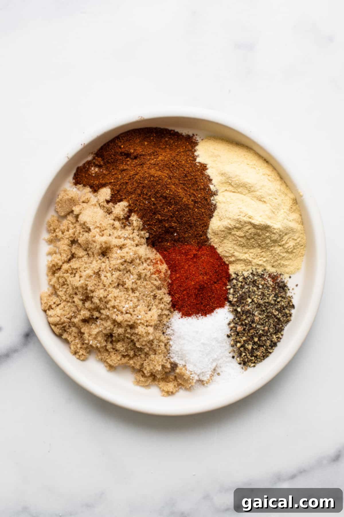 Pork Chop Seasoning Ingredients A selection of spices for pork chop dry rub arranged on a small plate.