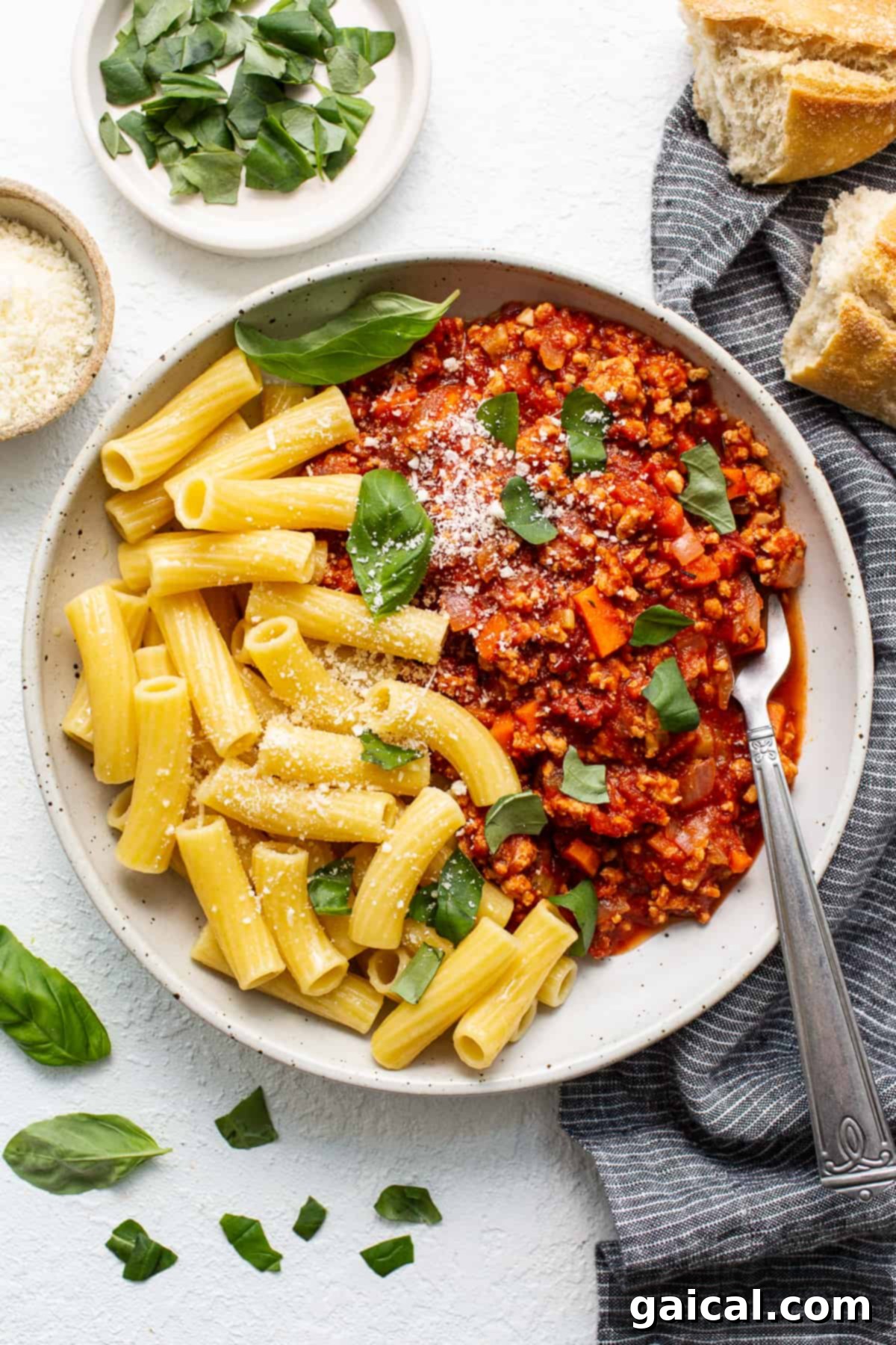 Delicious ground chicken bolognese served over pasta. Ground chicken bolognese served in a bowl with freshly cooked pasta, garnished with herbs.