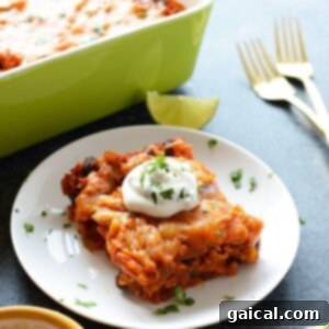 A chicken enchilada casserole topped with sour cream and limes.