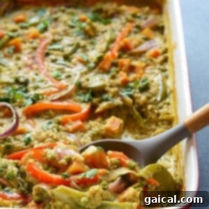A curry quinoa casserole garnished with vegetables and served with a spoon.