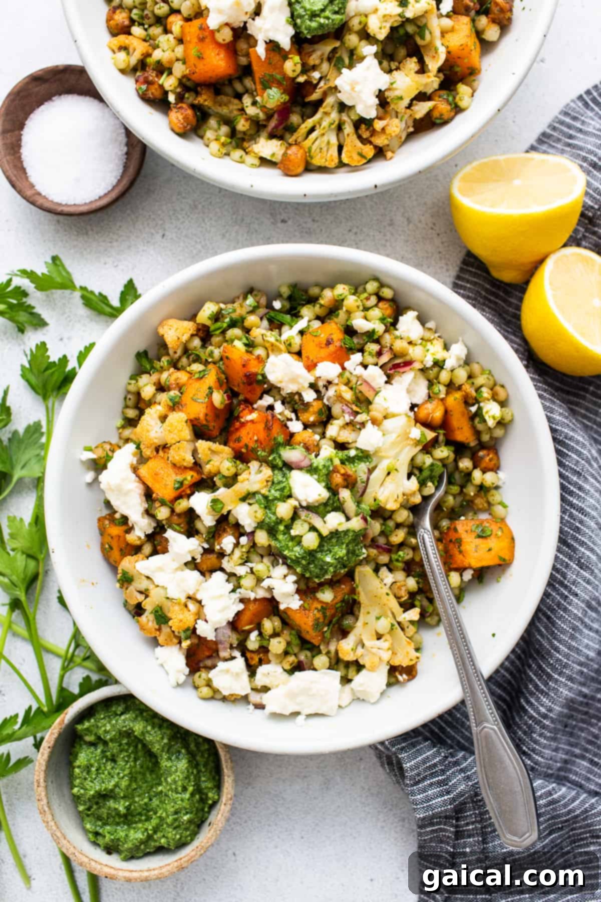 A beautifully presented bowl of Israeli couscous salad, featuring pearls of couscous, roasted vegetables, and green pesto.