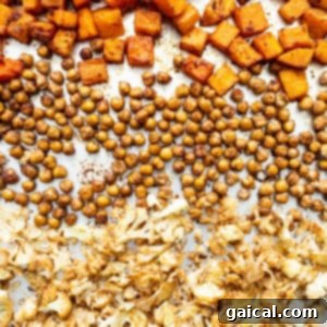 A single baking sheet filled with an assortment of perfectly roasted butternut squash, chickpeas, and cauliflower.