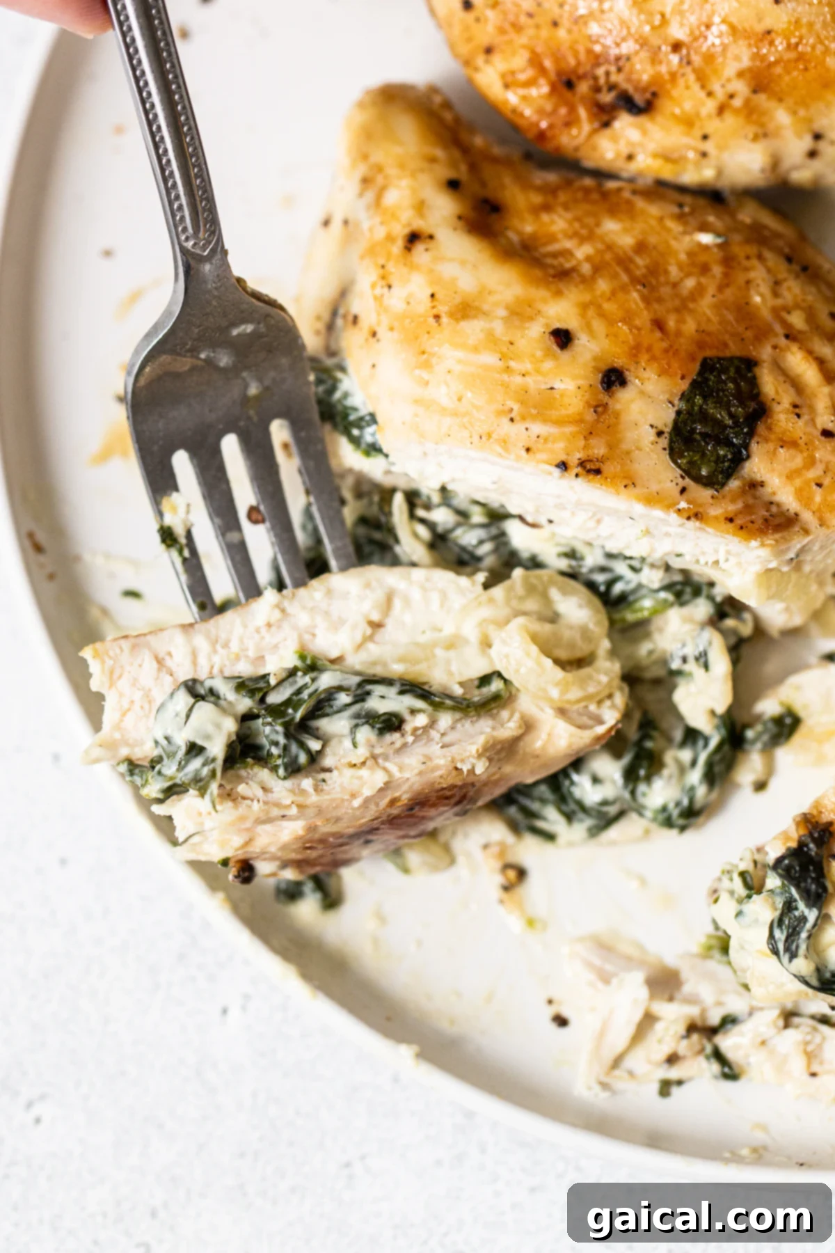 Sliced Spinach Stuffed Chicken Breast A close-up of a sliced spinach stuffed chicken breast on a plate, revealing the creamy filling.