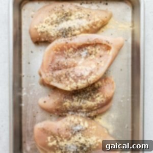 Cheesy Spinach Stuffed Chicken 10 Seasoned chicken breasts on a baking sheet, ready for stuffing.