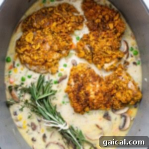Chicken, mushrooms, and rosemary sprigs arranged in a skillet for baking.