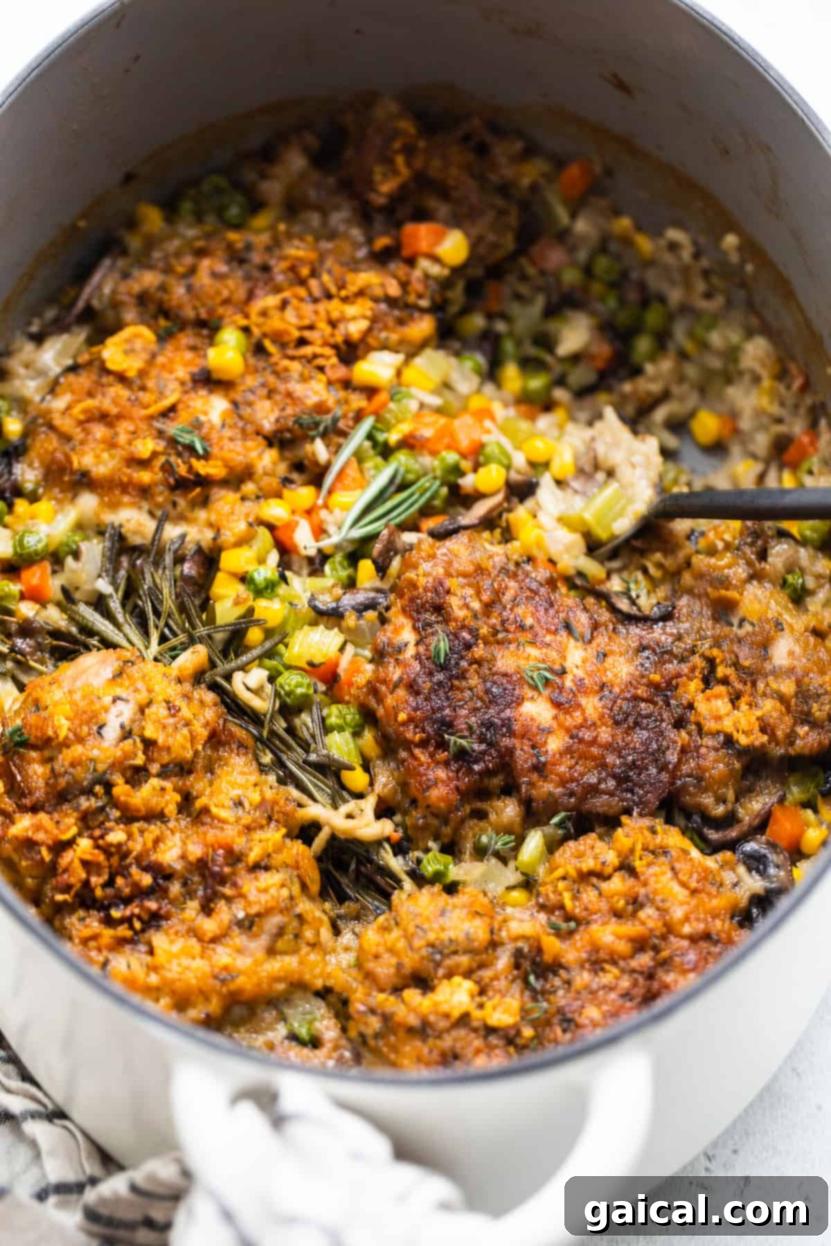 A serving spoon scooping out a generous portion of chicken pot pie from the skillet.