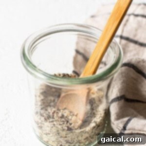 A glass jar with seeds and a wooden spoon.