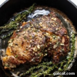 Cast iron steak in a pan with herbs and butter.