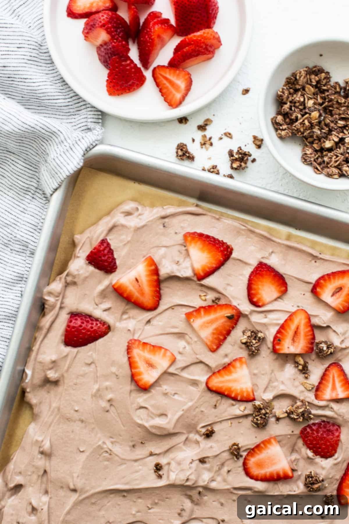 Frozen yogurt bark before freezing Frozen yogurt bark topped with strawberries.