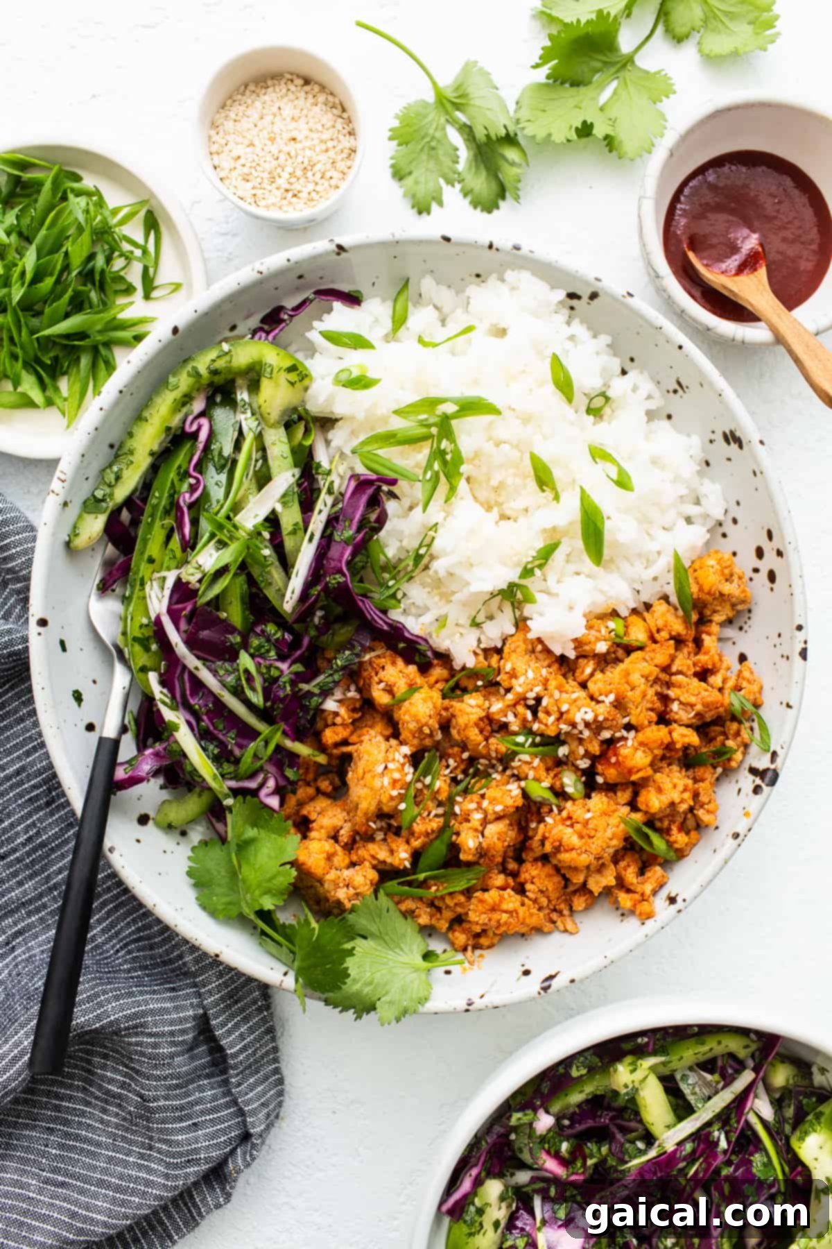 Spicy Korean Ground Chicken Bowls 2 Ground chicken bowls topped with fresh green onions and sesame seeds, showcasing vibrant colors and enticing textures.