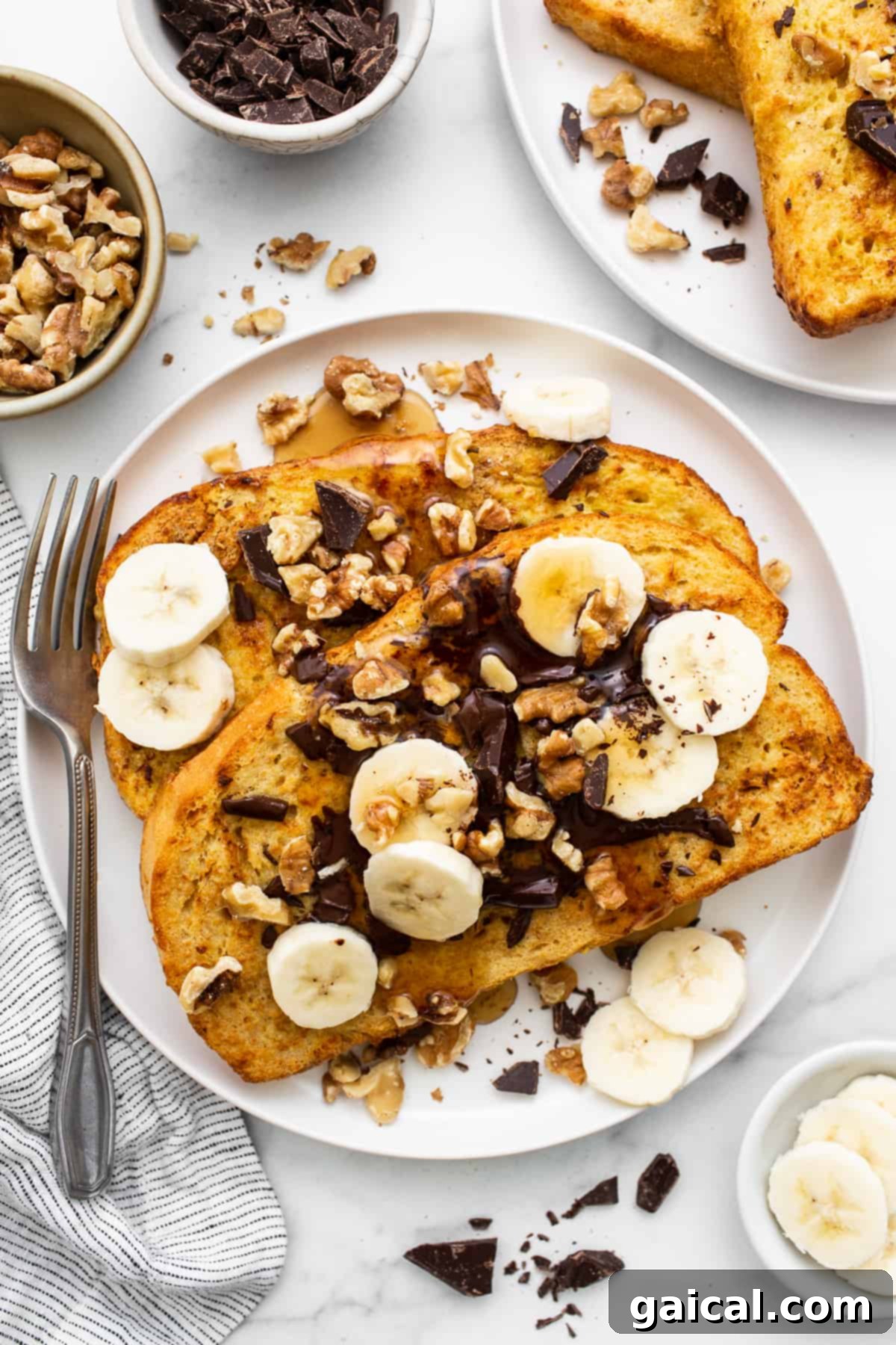 A plate of golden Air Fryer Chunky Monkey French Toast, topped with melted chocolate, roasted walnuts, and sliced bananas, ready to be enjoyed.