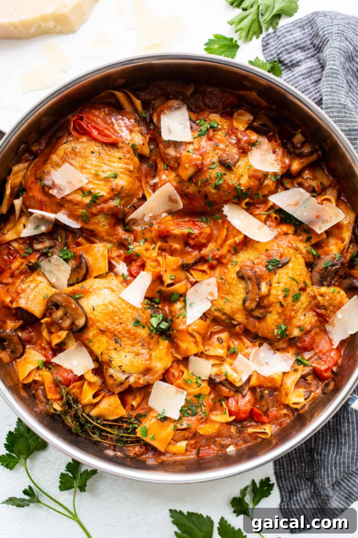 A comforting one-pot pappardelle pasta dish with tender chicken thighs, mushrooms, tomatoes, and shaved Parmesan. Pappardelle pasta with chicken thighs in a pot, garnished with fresh herbs and shaved Parmesan.
