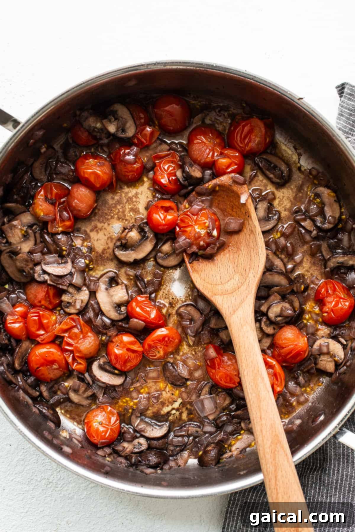 Mushrooms and tomatoes softening in a pan for a robust pasta sauce. Sautéing mushrooms and cherry tomatoes in a skillet, creating a vibrant base for the pasta sauce.