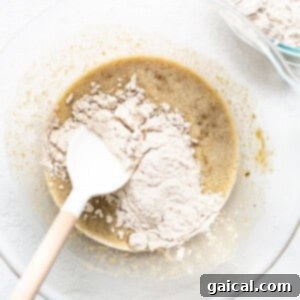 Adding dry ingredients to wet ingredients in a large mixing bowl