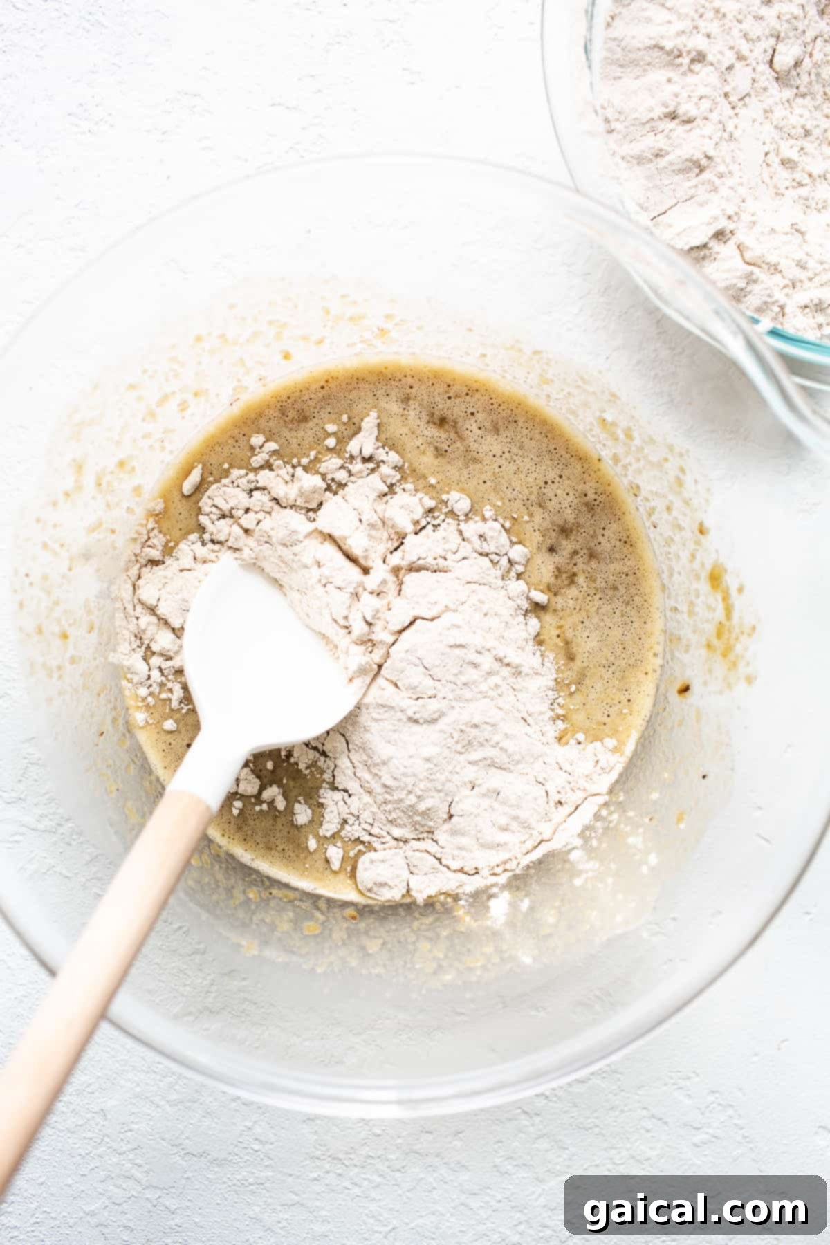 A close-up of unbaked Bananas Foster muffin batter with banana slices pressed into the top