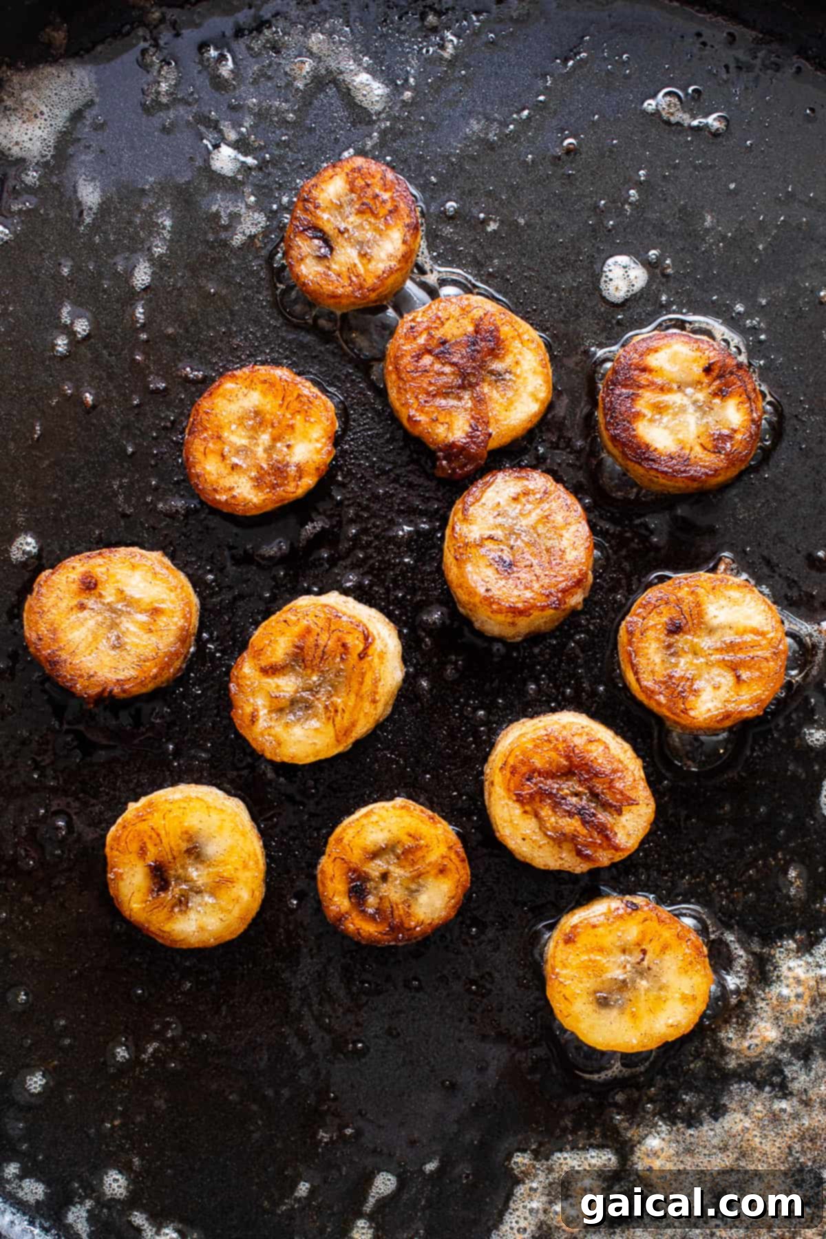 Sliced bananas caramelizing in a pan with butter and rum for the Bananas Foster topping