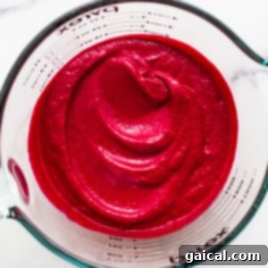Vibrant pink beet puree in a measuring cup, showcasing the smooth sauce consistency.