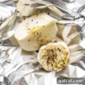 Garlic and onion seasoned and wrapped in foil for roasting.