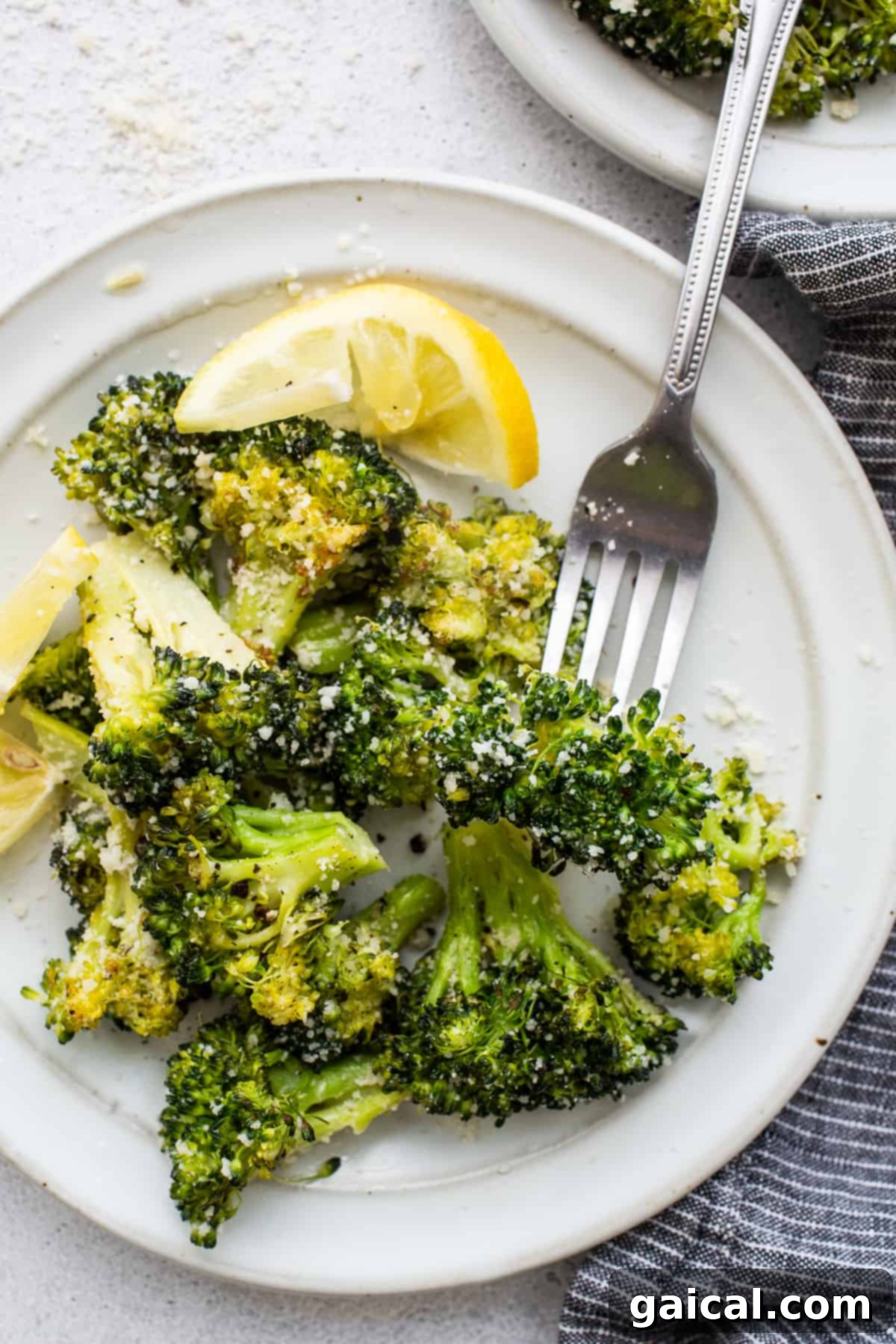 Perfectly Roasted Broccoli Recipe Perfectly roasted broccoli florets on a white plate with a fork, ready to be enjoyed as a delicious and healthy side dish.