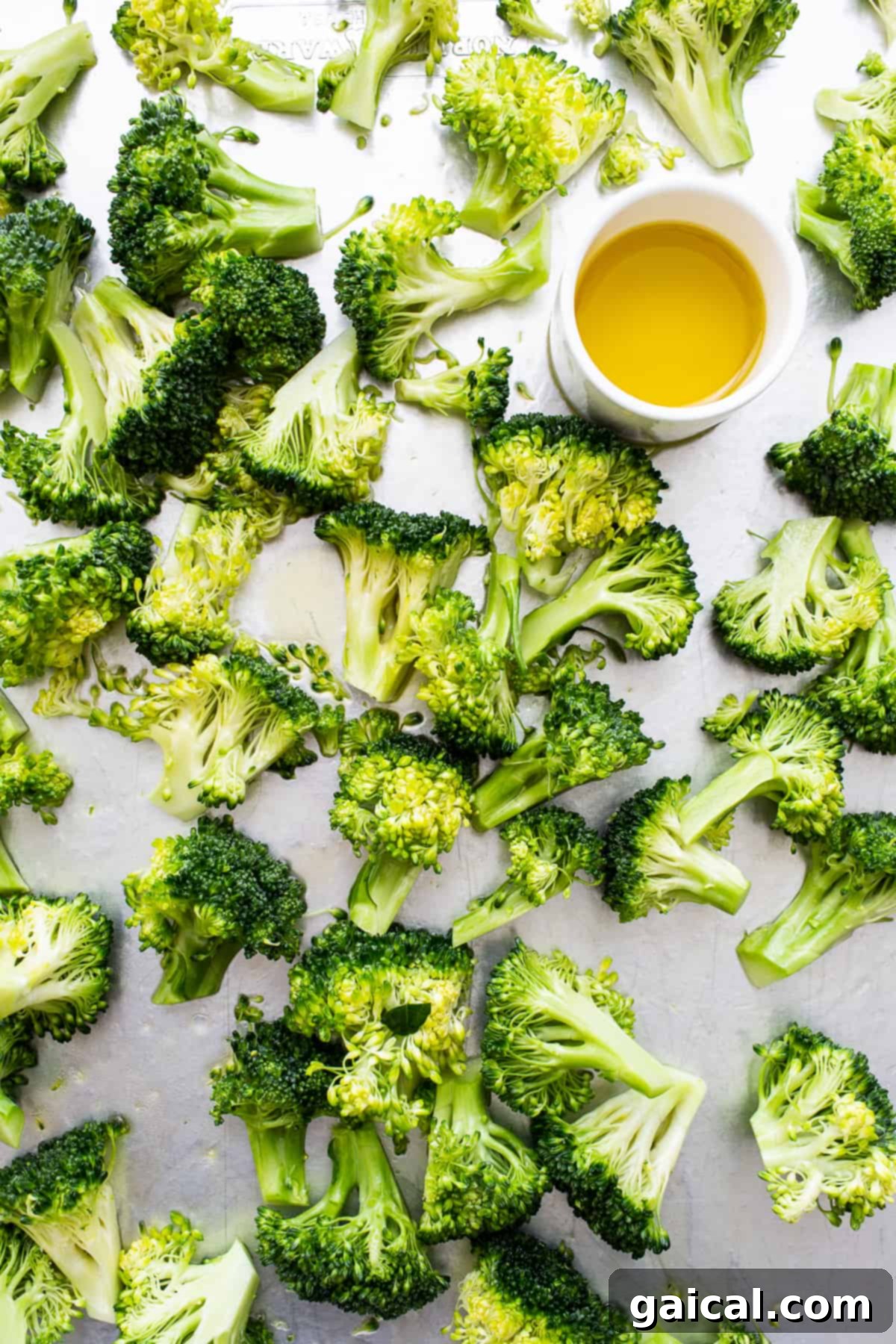 Broccoli and Olive Oil Fresh broccoli florets and a bowl of golden olive oil, highlighting the essential ingredients for roasting.