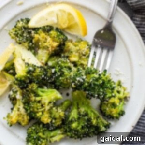 Roasted broccoli on a plate, garnished with a sprinkle of cheese.