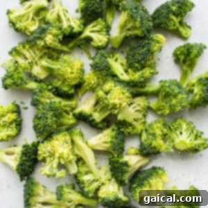 A pile of chopped broccoli florets on a clean white surface, prepped for roasting.