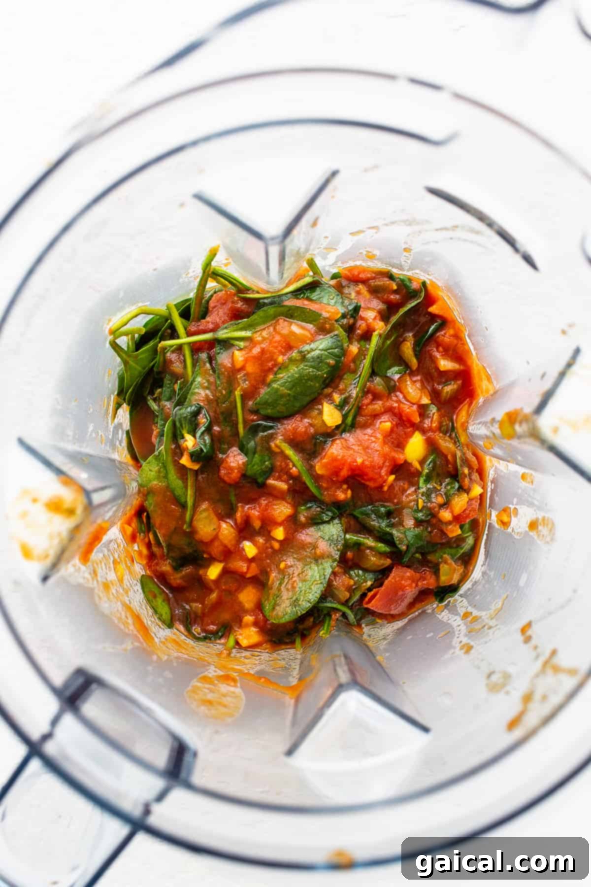 Spinach and Tomato Sauce Blending for a Silky Curry Base Vibrant spinach and rich crushed tomato sauce blending smoothly in a high-powered blender, creating a lush puree for the curry.