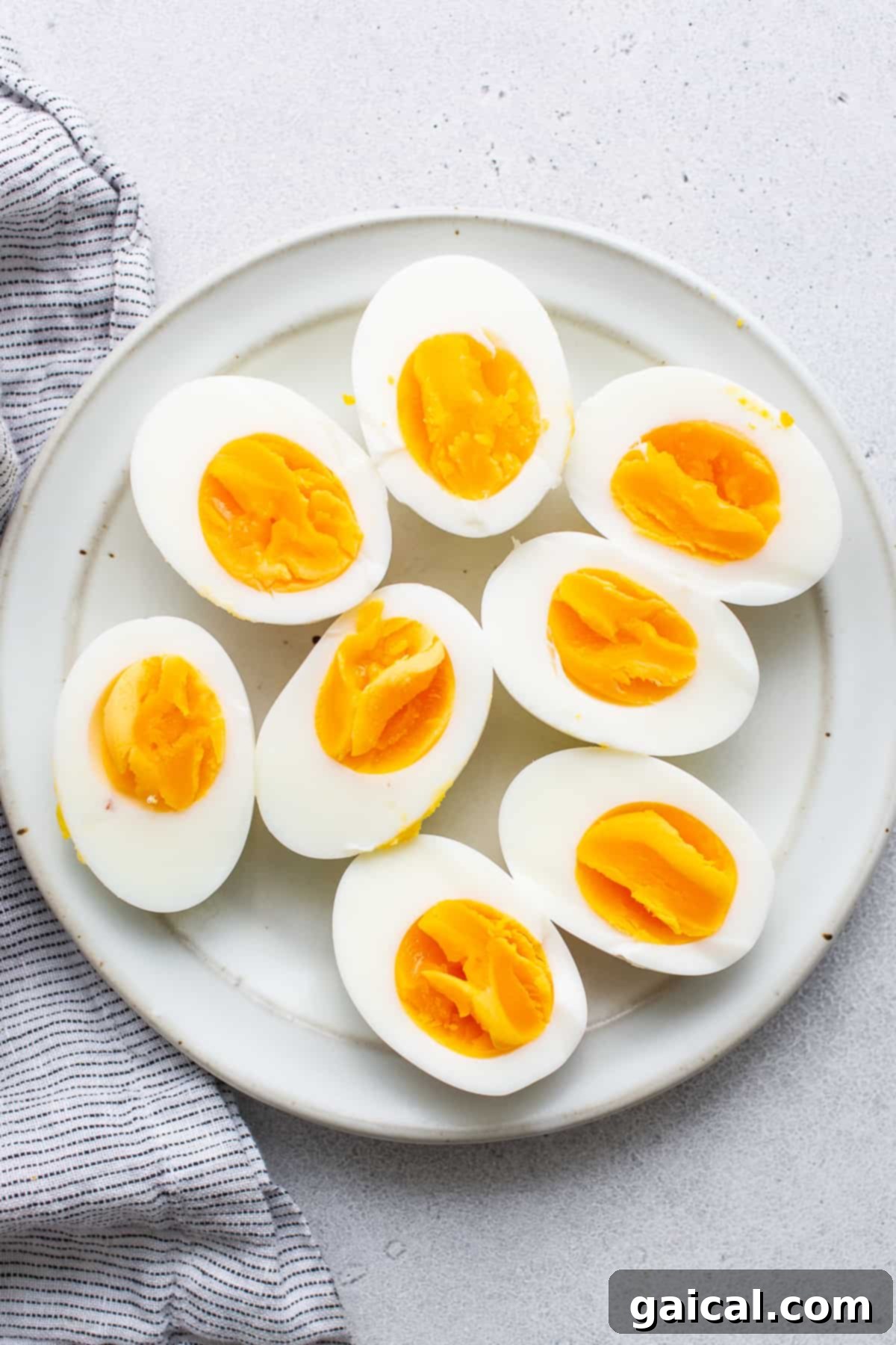 Perfectly Cooked Egg Halves, Ready for Any Dish Two perfectly cooked hard boiled egg halves, showcasing their vibrant yellow yolks and firm whites, attractively displayed on a clean white plate.