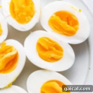 A plate of air fryer hard boiled eggs, perfectly cooked and ready to eat, sliced and whole.