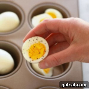 Effortless Air Fryer Hard Boiled Eggs 3 A person expertly arranging eggs in a muffin tin, preparing to hard boil them using an oven, showcasing an alternative cooking method.