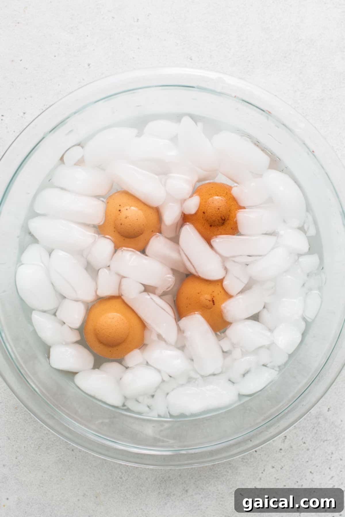 Essential Ice Bath for Easy-Peel Hard Boiled Eggs Freshly cooked hard boiled eggs immersed in a clear glass bowl filled with ice water, showcasing the crucial ice bath step for easy peeling.